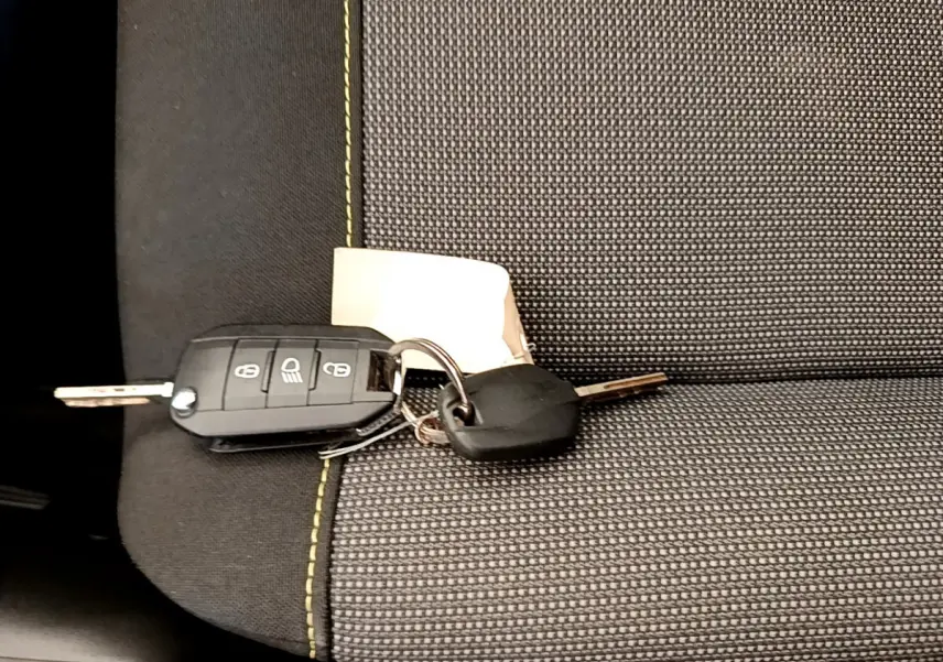 Clé de voiture Citroën C3 posée sur siège tissu gris à surpiqûres vertes, vue rapprochée de l'intérieur