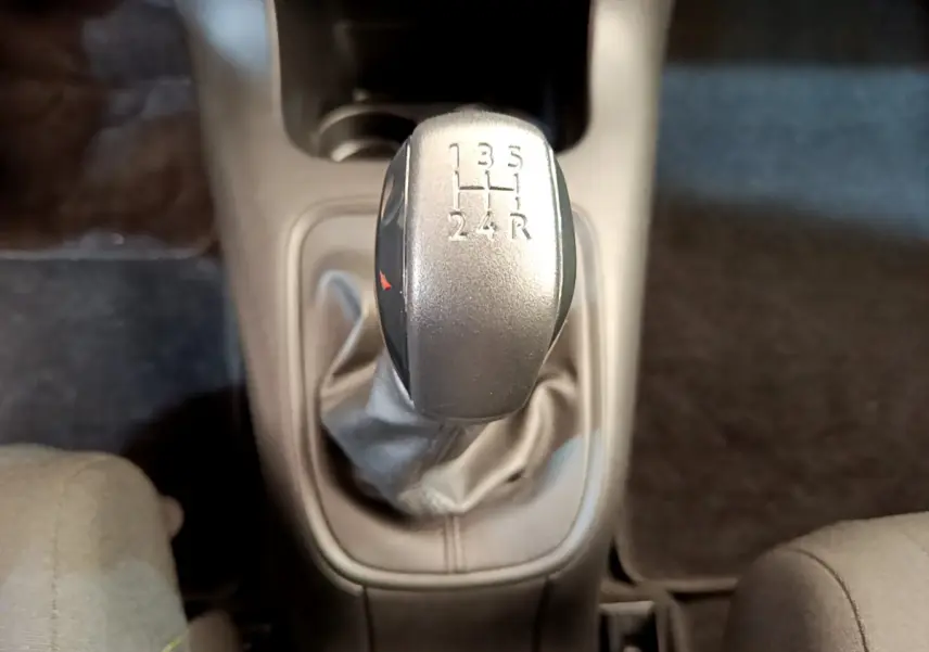 Le levier de vitesses manuel gris de la CITROEN C3 PureTech 82 S&S BVM Graphic vu de dessus, entouré de sièges tissu.