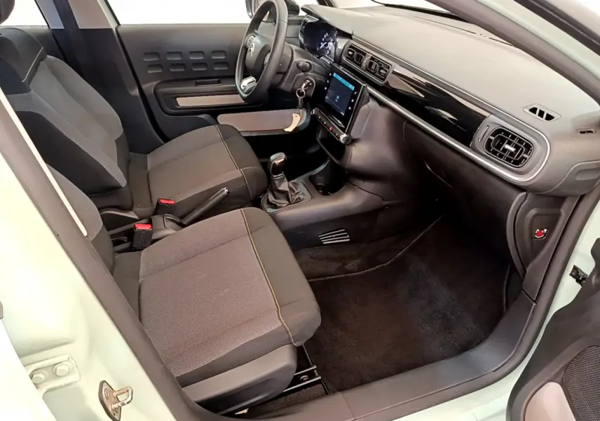 Intérieur avant droit d'une Citroën C3 vert 2019, montrant sièges tissu, volant multifonctions et écran tactile central.