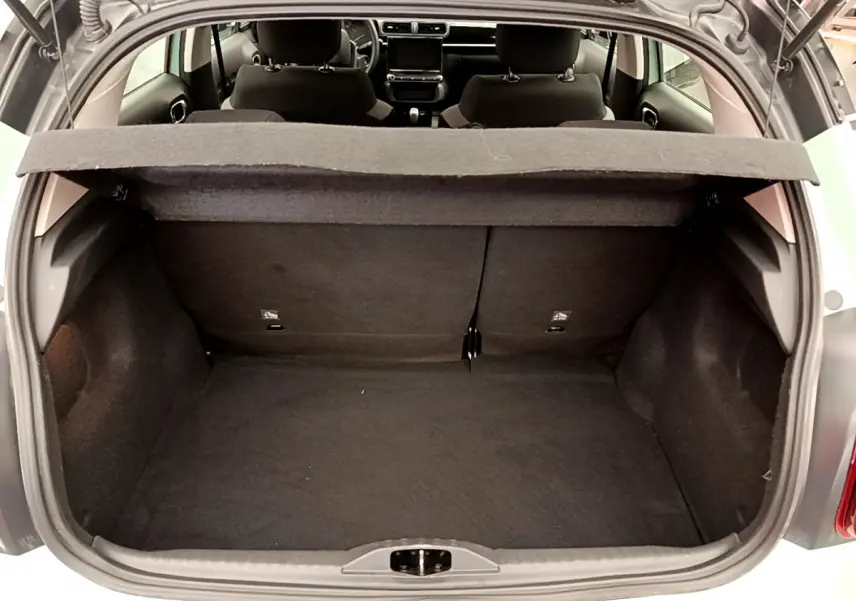 Vue du coffre ouvert d'une Citroën C3 vert 2019, montrant l'intérieur spacieux et la tablette de séparation.