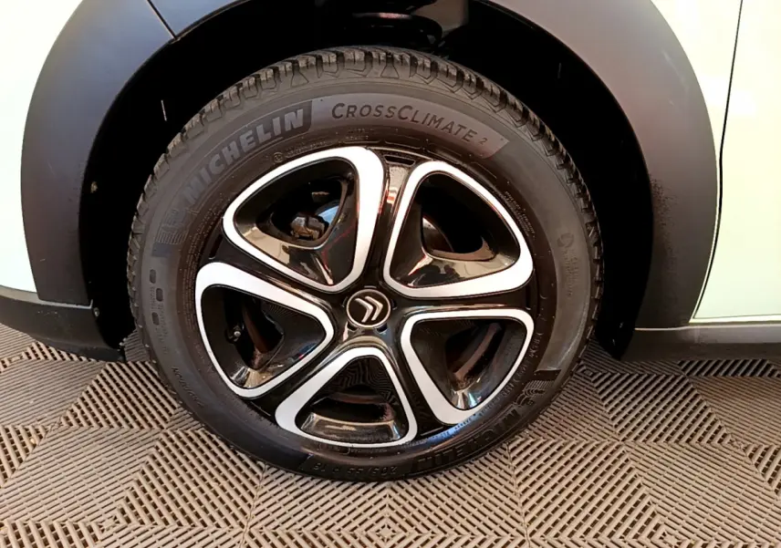 Gros plan sur la roue avant droite d'une Citroën C3 vert clair avec jante noire et argentée au design moderne.