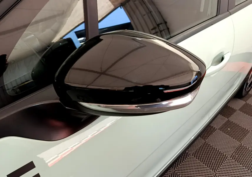Rétroviseur côté gauche noir brillant avec clignotant intégré sur Citroën C3 vert vue rapprochée.