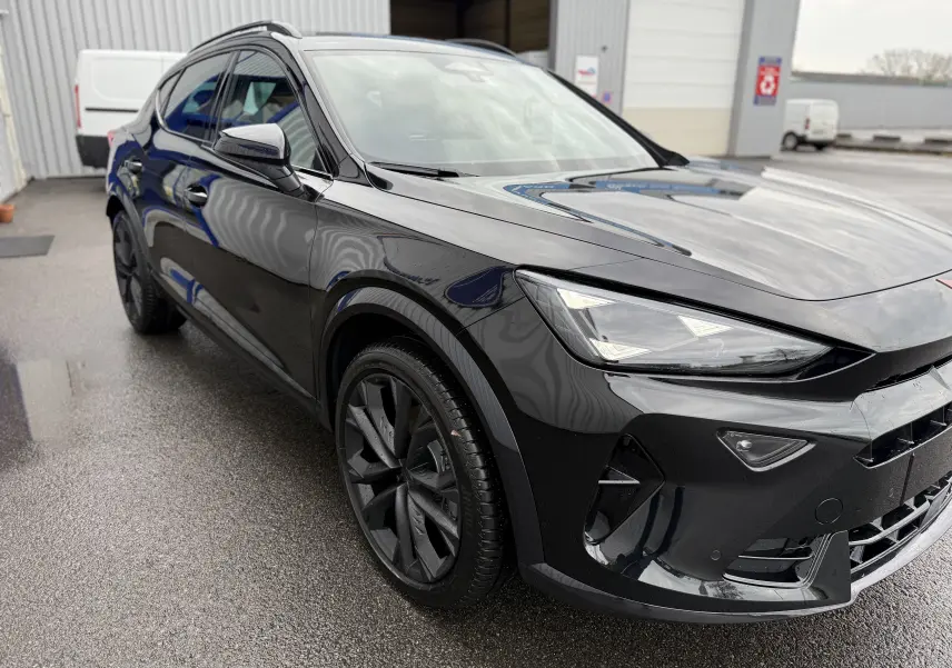 Vue 3/4 avant gauche d’un CUPRA Formentor 1.5 eHybrid 204 noir minuit avec jantes noires et phares LED allumés.