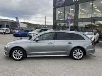 Audi A6 Avant 2.0 TDI gris métal vue de profil côté gauche, finition S-Line avec jantes alliage, stationnée devant un bâtiment.