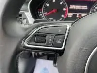 Gros plan sur les commandes au volant d'une Audi A6 Avant 2.0 TDI gris métal, mettant en valeur les boutons multifonctions.