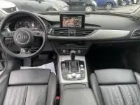Vue intérieure de l’Audi A6 Avant 2018 gris métal, montrant le tableau de bord, volant, écran central et sièges cuir noirs.