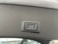 Bouton d'ouverture électrique du hayon sur l'intérieur d'un Audi A6 Avant gris métal 2018, vue rapprochée.