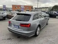 Audi A6 Avant 2.0 TDI S-Line gris métal vue 3/4 arrière droit sur parking avec toit ouvrant fermé.