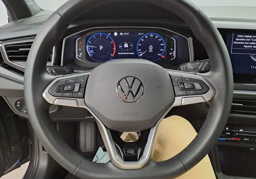 Vue intérieure centrée sur le volant noir du Volkswagen Taigo 2025 avec tableau de bord numérique et commandes intégrées.