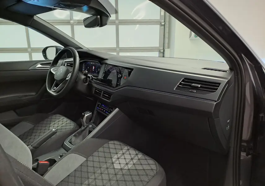 Vue intérieure côté conducteur du Volkswagen Taigo 1.0 TSI 116 DSG7 R-Line Edition avec sièges tissu gris à motifs.