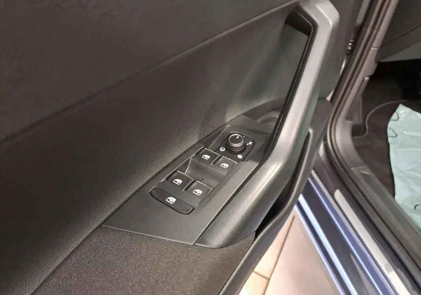 Gros plan sur la commande des vitres et rétroviseurs sur la porte avant gauche d’un Volkswagen Taigo gris cendré.