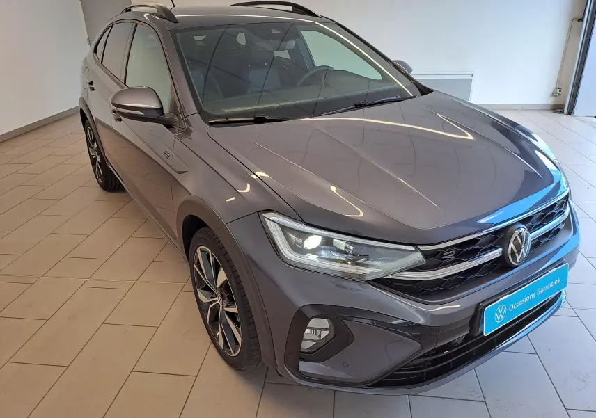 Vue 3/4 avant droite du Volkswagen Taigo gris cendré avec jantes alliage 18 pouces et calandre R-Line distinctive.