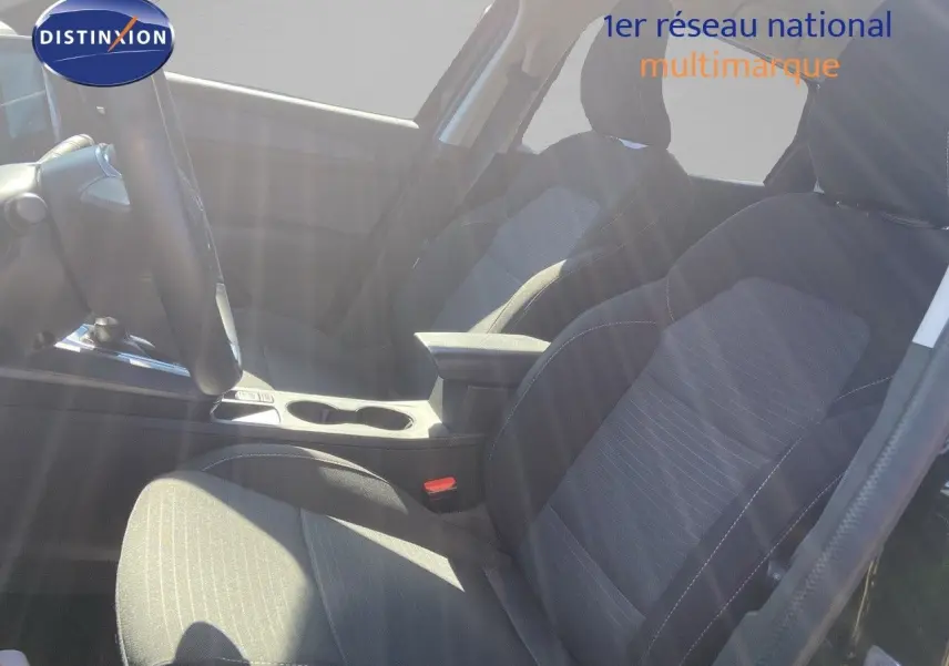 Vue intérieure côté conducteur du Renault Arkana 2023, sièges tissu gris noir avec accoudoir central.