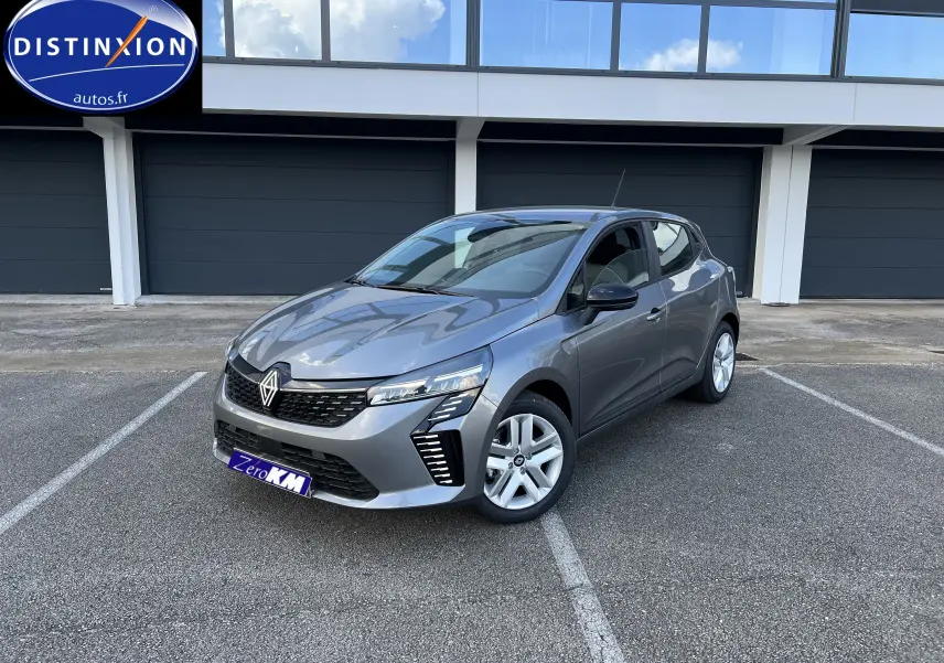 Renault Clio V gris schiste vue 3/4 avant droit, avec jantes alliage et feux LED distinctifs sur parking.