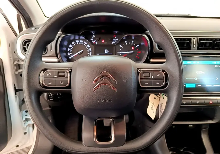 Vue rapprochée du volant noir de la Citroën C3 blanche 2019 avec tableau de bord et écran tactile visible à droite.