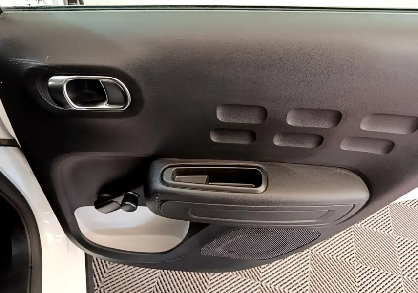 Vue intérieure côté gauche de la porte avant noire avec poignée chromée d'une Citroën C3 blanche 2019.