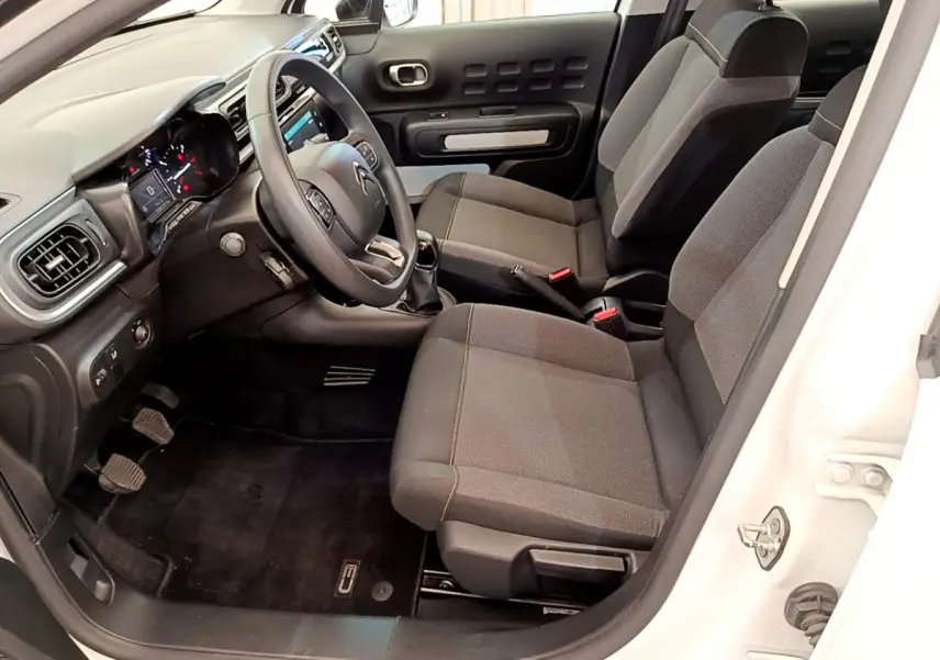 Intérieur avant droit de la Citroën C3 blanche 2019, sièges tissu gris et tableau de bord avec écran tactile.