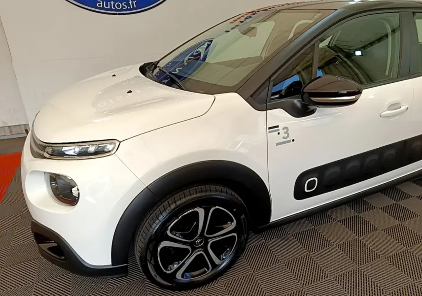 Vue 3/4 avant gauche d'une Citroën C3 blanche avec protections latérales noires et jantes noires distinctives.
