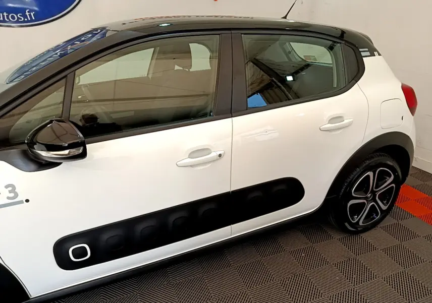 Vue côté gauche d'une Citroën C3 blanche avec toit noir et protections latérales noires caractéristiques.