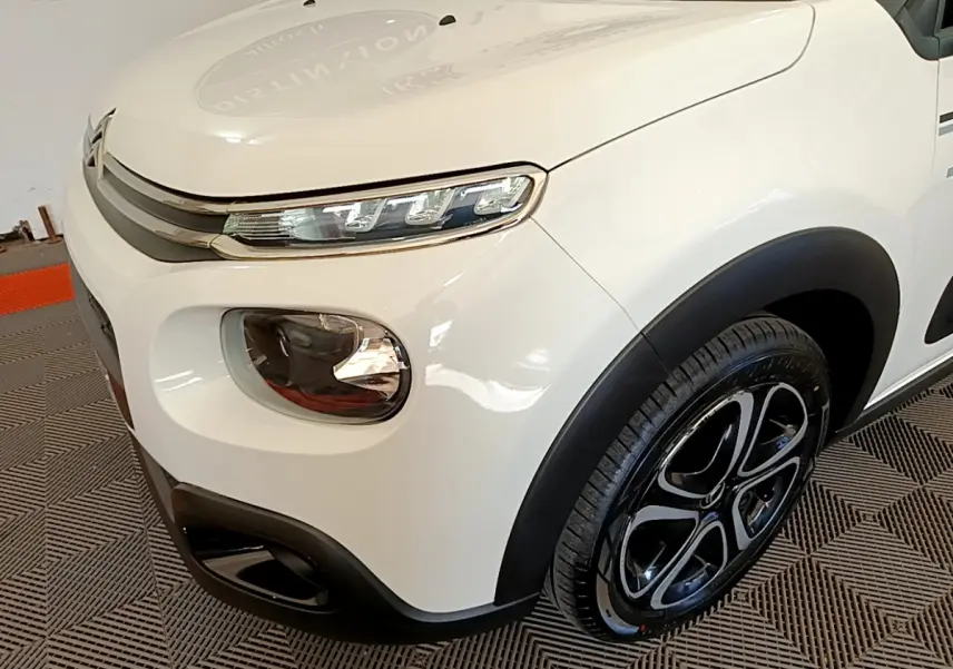 Vue 3/4 avant droit d'une Citroën C3 blanche avec phares LED et jantes noires distinctives.