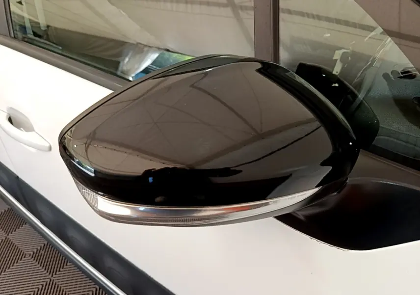 Rétroviseur noir brillant côté gauche d'une Citroën C3 blanche 2019, avec clignotant intégré visible.