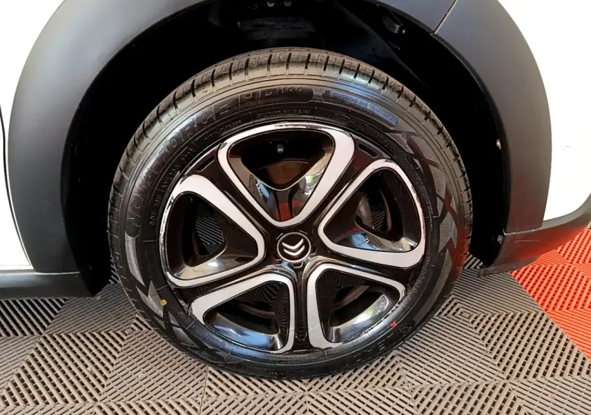 Gros plan sur la roue avant droite noire et chrome d'une Citroën C3 blanche 2019 avec logo Citroën central.