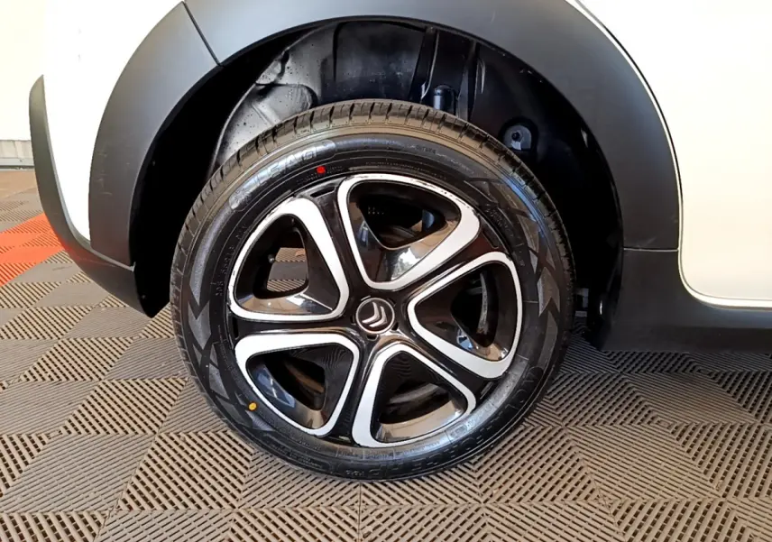 Gros plan sur la roue avant droite d'une Citroën C3 blanche, mettant en valeur la jante noire et argentée au design moderne.