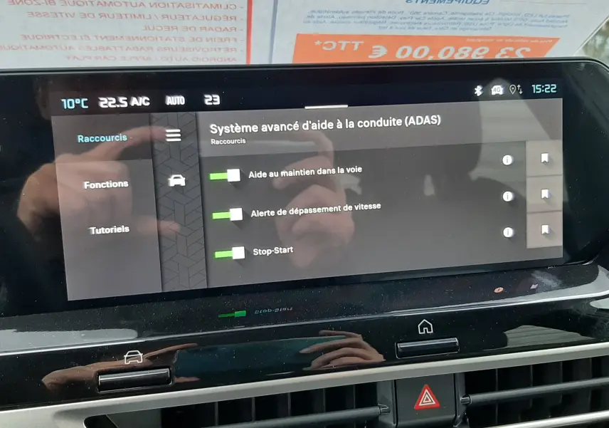 Vue intérieure de l'écran tactile du tableau de bord de la Citroën C4 blanche avec toit noir, affichant les aides à la conduite activées.