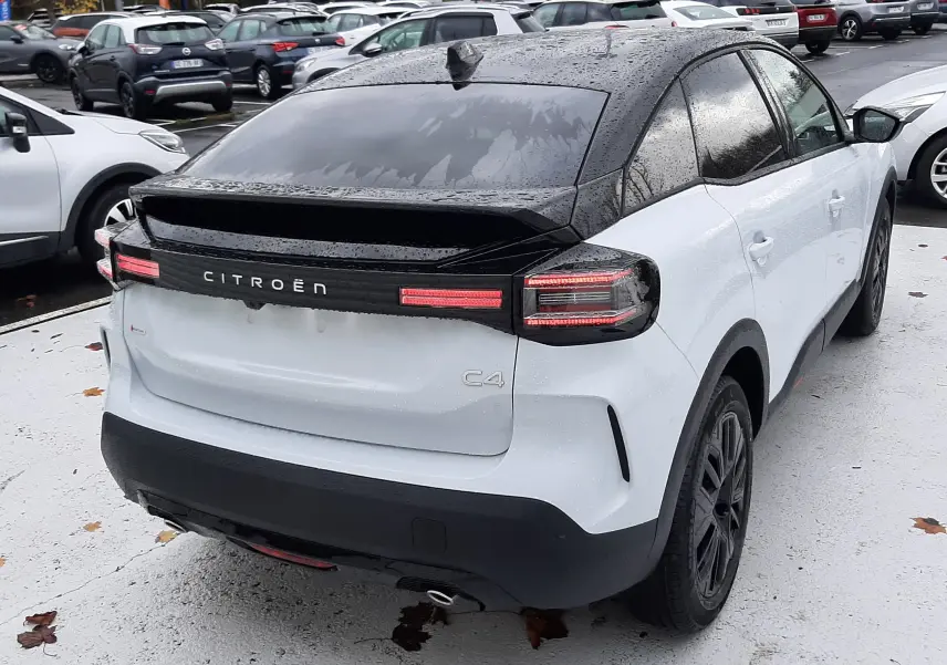 Vue 3/4 arrière droite d'une Citroën C4 blanche Okenite avec toit noir Perla et feux arrière LED distinctifs.