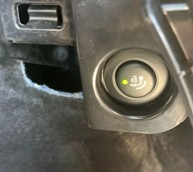 Gros plan sur bouton de déverrouillage électrique du coffre dans le coffre d'un BMW X3 blanc 2023.