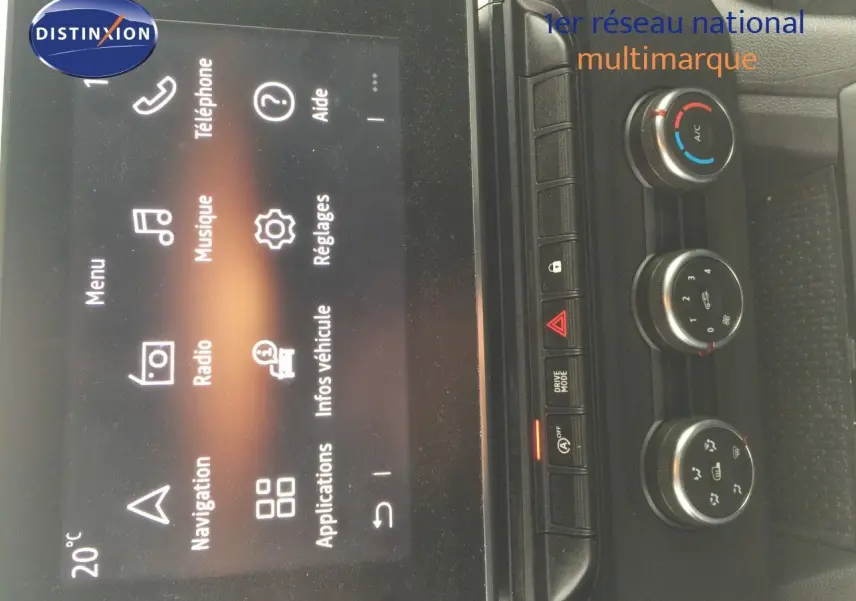 Vue rapprochée de la console centrale du Renault Kangoo blanc 2023, avec écran tactile et commandes de climatisation.