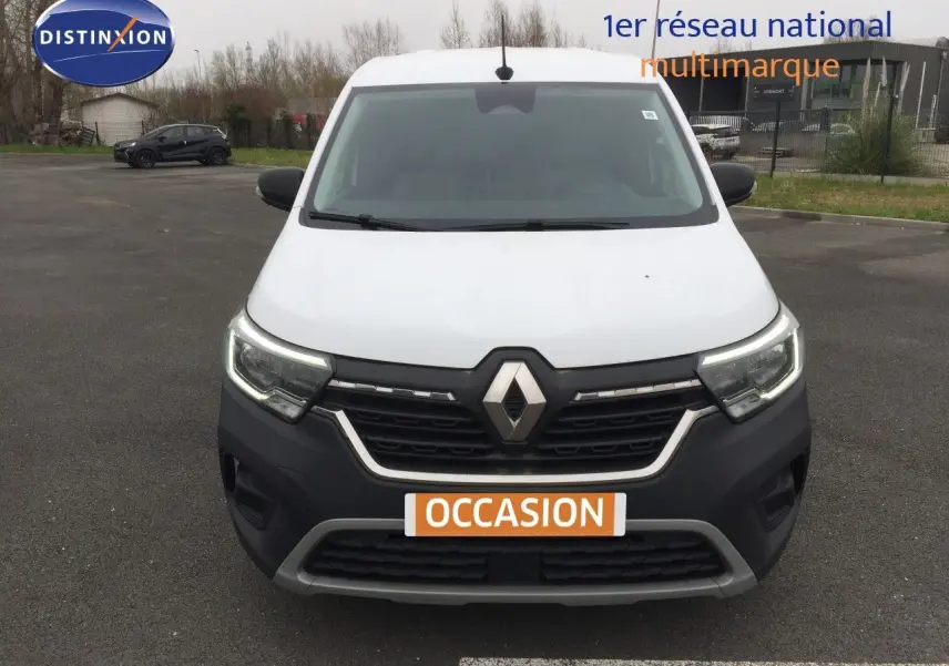 Vue de face du Renault Kangoo Extra blanc 2023 avec calandre noire et feux LED allumés sur parking.