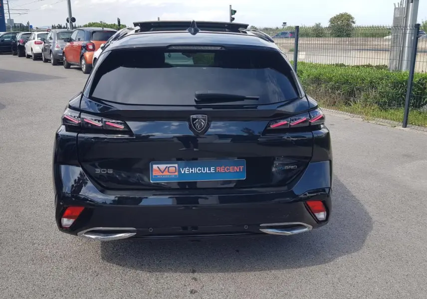 Vue arrière d’une Peugeot 308 SW PHEV 225 e-EAT8 GT noire avec feux LED et double sortie d’échappement chromée.