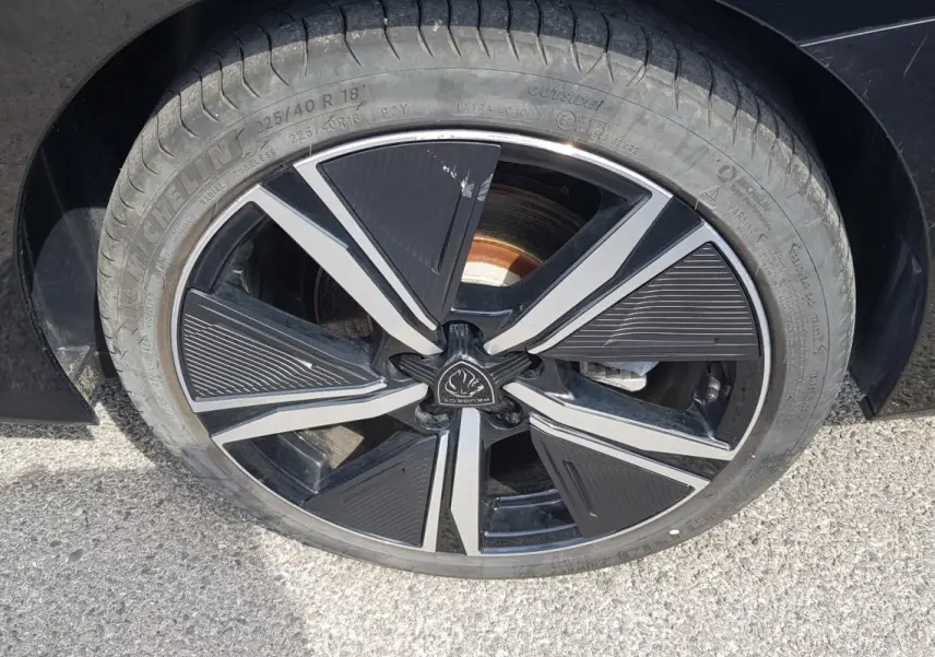 Gros plan sur la jante alliage noire et argentée de 18 pouces d'une Peugeot 308 SW PHEV 225 e-EAT8 GT noire.