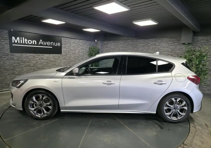 Vue de profil côté gauche d'une Ford Focus 2024 gris lunaire avec jantes alliage 17'' et vitres surteintées.