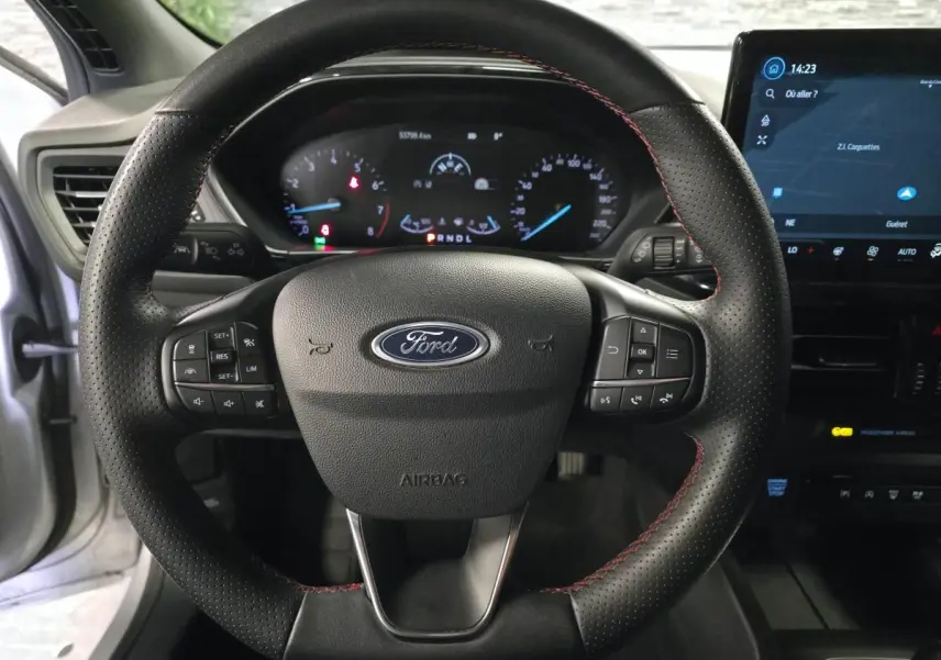 Vue intérieure centrée sur le volant perforé noir avec surpiqûres rouges de la Ford Focus 2024 gris lunaire.