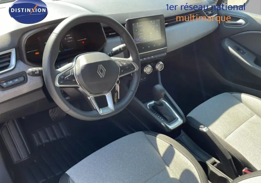 Vue intérieure de la Renault Clio 2025, tableau de bord et volant multifonction avec sellerie tissu gris clair.