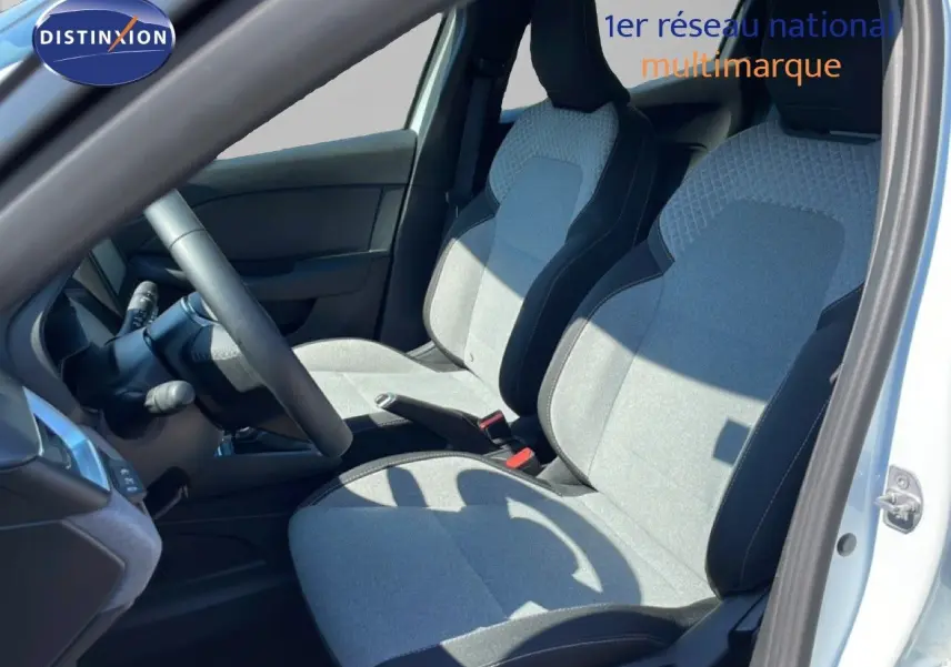 Vue intérieure côté conducteur de la Renault Clio blanche glacier 2025, sièges tissu gris clair avec contours noirs.