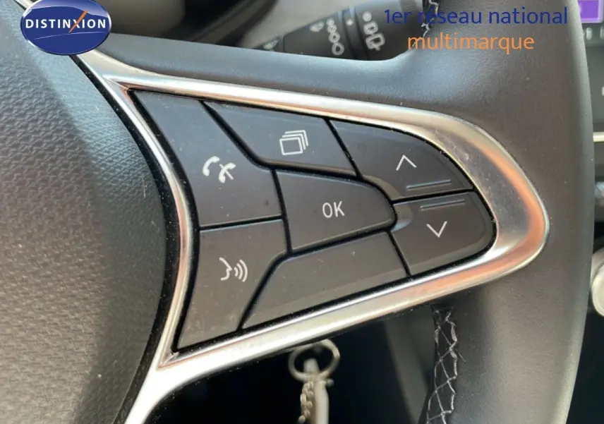 Gros plan sur les commandes multifonctions au volant en cuir noir de la Renault Clio hybride 2025.