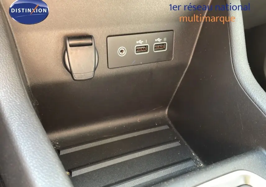 Gros plan sur la console centrale noire avec prises USB et prise 12V dans une Renault Clio Blanc Glacier.