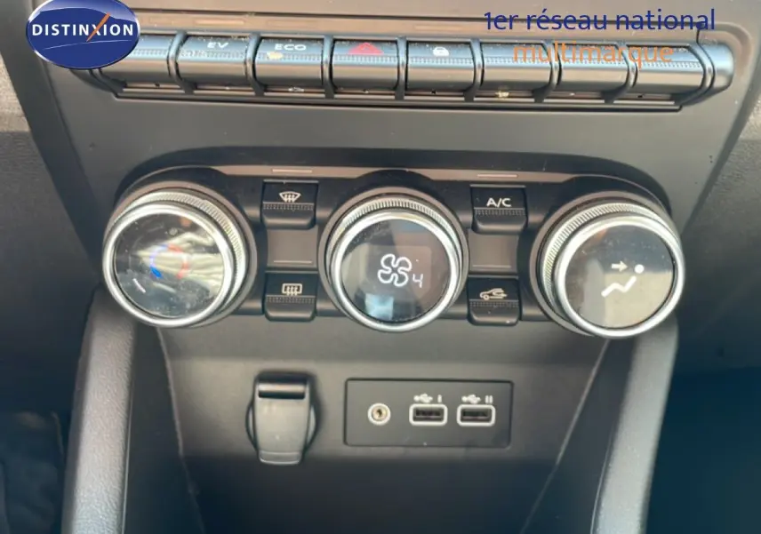 Vue rapprochée des commandes de climatisation et des ports USB du tableau de bord d'une Renault Clio blanche Glacier.