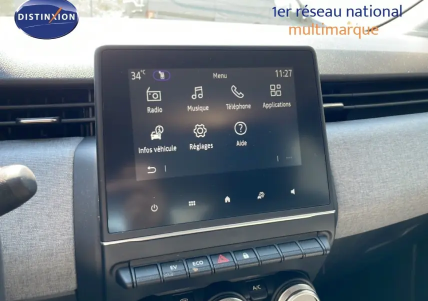 Vue rapprochée de l’écran tactile central et des commandes de la Renault Clio blanche Glacier, version hybride 2025.