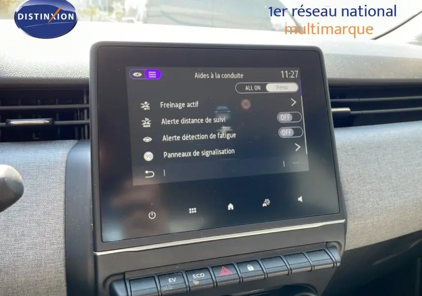 Vue intérieure centrée sur l'écran tactile du tableau de bord de la Renault Clio hybride blanche, affichant les aides à la conduite.
