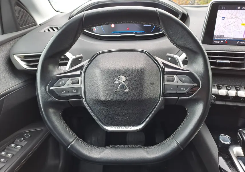 Vue rapprochée du volant en cuir noir du Peugeot 3008 2018 avec commandes intégrées et tableau de bord digital.