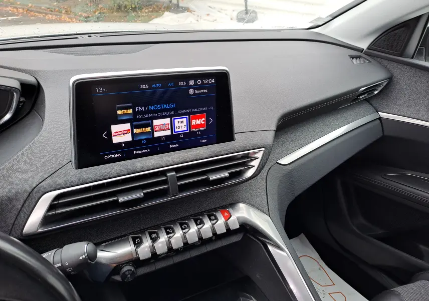 Vue intérieure côté passager du tableau de bord gris du Peugeot 3008 blanc avec écran tactile et commandes piano.