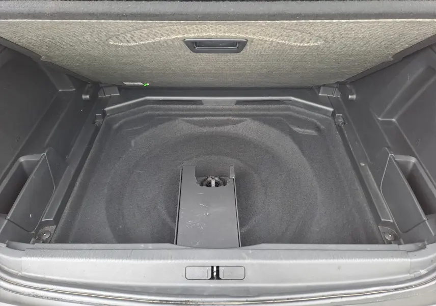 Coffre ouvert du Peugeot 3008 blanc, vue plongeante sur le compartiment de rangement sous plancher.
