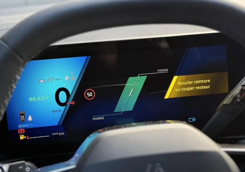 Tableau de bord numérique du Renault Espace VI hybride, affichant vitesse et alertes, vu depuis le volant.
