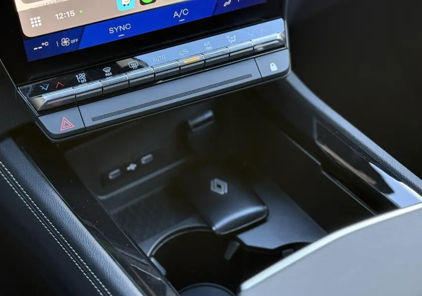 Gros plan sur la console centrale noire du Renault Espace VI avec commandes climatisation et chargeur sans fil visible