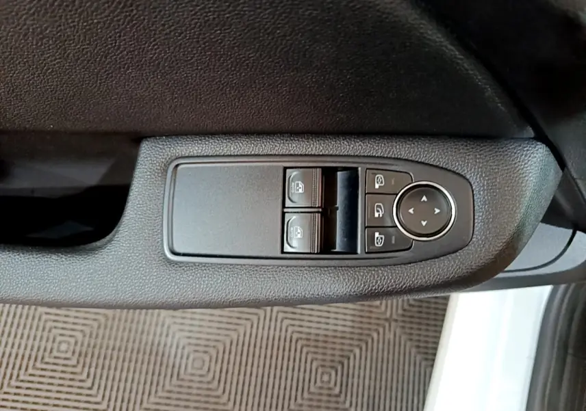 Gros plan sur les commandes de lève-vitres et réglage des rétroviseurs côté conducteur d'une Renault Clio blanche 2020.