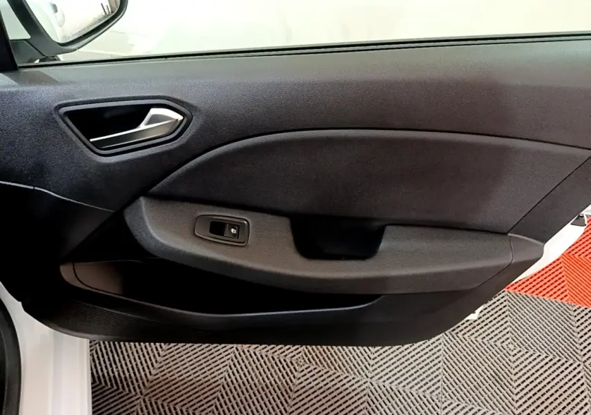 Gros plan sur la porte intérieure côté gauche d'une Renault Clio Business blanche, avec poignée argentée et bouton de vitre électrique.